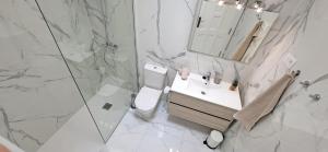 a bathroom with a toilet and a sink and a mirror at Ferienwohnung OCEAN SOUNDS 2 in Gran Tarajal +24 photos