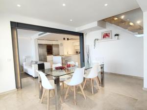uma sala de jantar com uma mesa de vidro e cadeiras brancas em Nereo - Heatable Pool & Sea View na Alcúdia