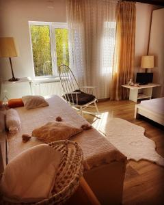 um quarto com uma cama, uma cadeira e uma janela em Casa din Poiana Garâna em Garana