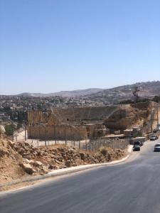una carretera con coches estacionados al costado de una colina en Bahaa, en Jerash