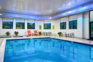 une piscine dans un hôtel avec des chaises et des tables rouges dans l'établissement Hilton Richmond Hotel & Spa Short Pump, à Richmond