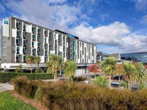 a large building with palm trees in front of it at ibis Budget Auckland Airport in Auckland