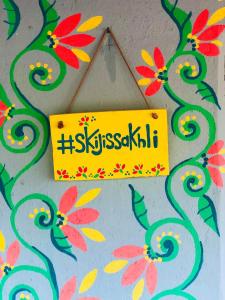 a yellow sign hanging on a wall with flowers at Skijis Sakhli in Zenobani