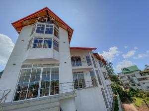 a tall white building with a red roof at Villa Moon Light Nuwara Eliya in Nuwara Eliya