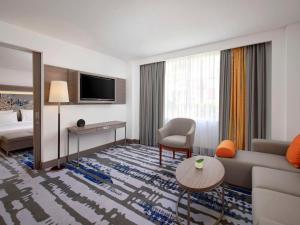 a hotel room with a couch and a table at Novotel Bali Ngurah Rai Airport in Kuta