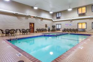 a large swimming pool in a building with tables and chairs at Comfort Inn in Sault Ste. Marie