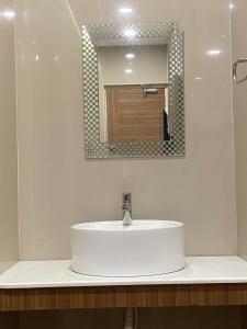 a bathroom with a white sink and a mirror at Hotel Sivas Regency in Theni