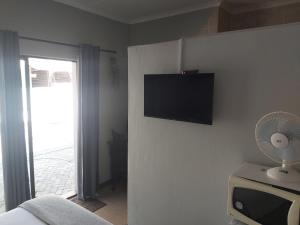 a bedroom with a tv on the wall and a fan at Day Zha Voux Guesthouse in Potchefstroom