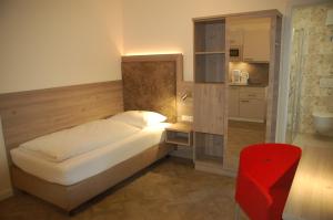 a small bedroom with a bed and a red chair at Aparthotel Weißenhorn in Weißenhorn