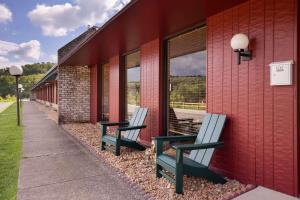 deux bancs assis sur le côté d'un bâtiment rouge dans l'établissement Travelodge by Wyndham Emlenton, à Emlenton