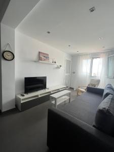 a white living room with a couch and a tv at Apartamento La Marquesa in Málaga