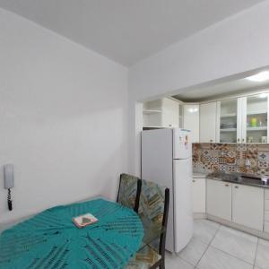 een witte keuken met een tafel en een koelkast bij Muito aconchegante perto do centro e da praia in Capão da Canoa
