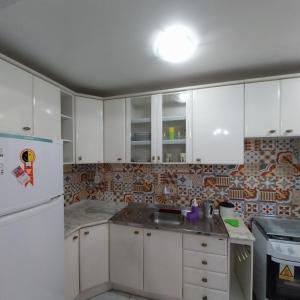 a kitchen with white cabinets and a white refrigerator at Muito aconchegante perto do centro e da praia in Capão da Canoa