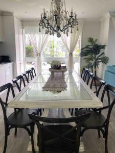 a dining room with a table with chairs and a chandelier at Boho Beach House in Vincentia