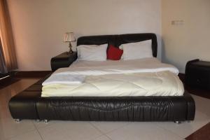 Ce lit se trouve dans un dortoir doté d'un cadre de lit en cuir. dans l'établissement Vincenzo trading, à Kigali