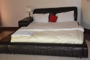 - un grand lit avec une tête de lit et des oreillers en cuir noir dans l'établissement Vincenzo trading, à Kigali