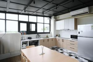 eine Küche mit einem weißen Kühlschrank und einem Tisch in der Unterkunft 谷園酒店公寓Good Garden Apartment in Taichung