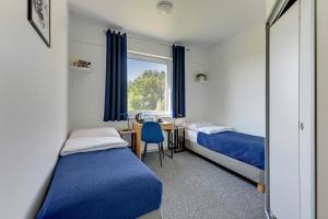 a bedroom with two beds and a desk and a window at Mile Gdansk Airport in Gdańsk
