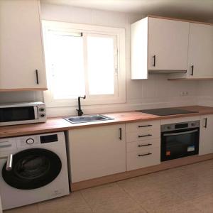 a kitchen with a washing machine and a microwave at NUEVO Apartamento Centro Lleida in Lleida