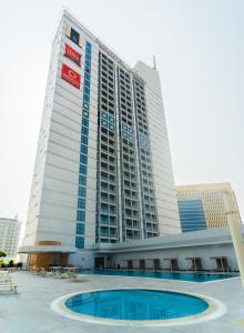 a tall building with a pool in front of it at Novotel Fujairah in Fujairah