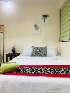 Un dormitorio con una cama blanca con una manta negra y roja en Persimmon Studios Condominium Cebu City, en Cebú