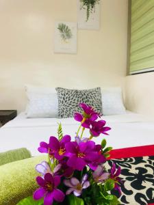 1 dormitorio con 1 cama con flores púrpuras en el primer plano en Persimmon Studios Condominium Cebu City, en Cebú