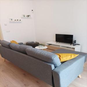 um sofá azul numa sala de estar com uma televisão em NUEVO Apartamento Centro Lleida em Lleida