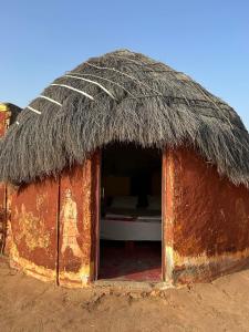 a small hut with a roof with a woman inside at Jaisalmer Safari Base & Camp in Khuri