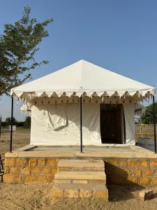 a white tent is set up in a field at Jaisalmer Safari Base & Camp in Khuri