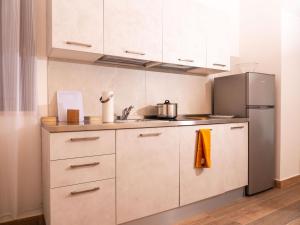 uma cozinha com armários brancos e um frigorífico de aço inoxidável em Appartamento Talamone - Santa Francesca em Talamone