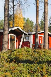 ein rotes Haus im Wald mit Bäumen in der Unterkunft Ivalo River Camping in Ivalo