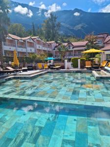 a pool at a hotel with mountains in the background at Hotel Des Neiges in Cilaos