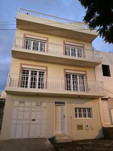 a large house with a balcony and two garage doors at Maison familiale à Tarrafal. in Tarrafal