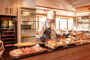 a chef preparing food in a restaurant kitchen at Monte Pana Dolomites Hotel in Santa Cristina Gherdëina