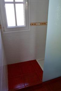 a bathroom with a shower with a window and a red floor at Dulce Valle Villas and Spa in El Paso