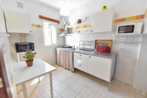 uma pequena cozinha com armários brancos e uma mesa em Casa Coro by SIERRA VIVA em Cortelazor
