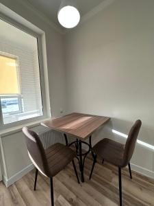 uma sala de jantar com uma mesa de madeira e 2 cadeiras em Отличная квартира в центре города Шымкент. ЖК Тумар апартамент em Shymkent