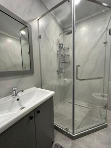 uma casa de banho branca com um chuveiro e um lavatório. em Отличная квартира в центре города Шымкент. ЖК Тумар апартамент em Shymkent