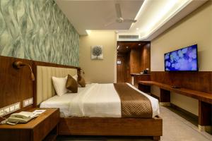 une chambre d'hôtel avec un lit et une télévision dans l'établissement Sundex Hotel, à Thanjavur