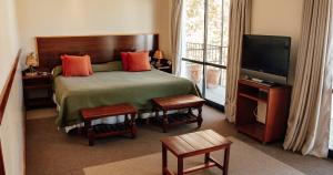 a bedroom with a bed and a flat screen tv at Hotel Los Sauces in Cafayate