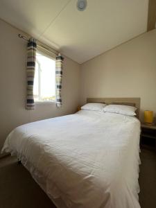a bedroom with a large white bed with a window at Luxurious Three Bedroom Caravan in Jaywick Sands