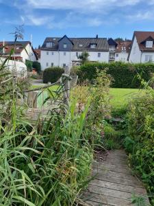 einen Holzweg durch einen Garten mit Häusern im Hintergrund in der Unterkunft Ferienwohnungen Schiffstatt in Guxhagen