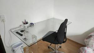 un bureau en verre avec une chaise à côté d'un lit dans l'établissement Ferienzimmer bei Thomas, à Ulm