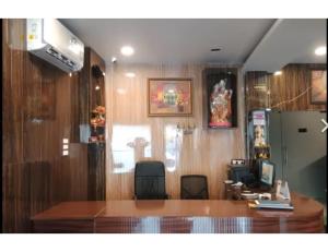 a room with a desk with chairs and a refrigerator at Hotel Saraswati International, Muzaffarapur in Muzaffarpur