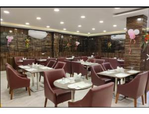 a restaurant with white tables and chairs and pink balloons at Hotel Saraswati International, Muzaffarapur in Muzaffarpur