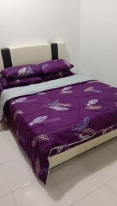 a bed with a purple blanket and pillows on it at 3 Bedroom Apartment with Pool and Beautiful View in Klebang, Ipoh in Chemor