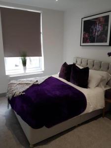 a bedroom with a bed with a purple blanket at Lovely 2-Bed Apartment in Stanford-le-Hope in Stanford-le-Hope