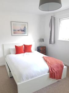a white bed with red pillows in a bedroom at Lovely 2-Bed Apartment in Stanford-le-Hope in Stanford-le-Hope