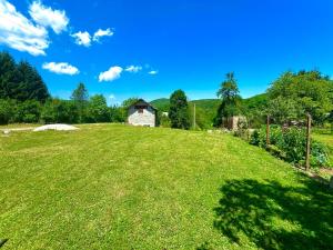 um grande campo relvado com um celeiro ao fundo em Guesthouse D&D em Ličko Petrovo Selo