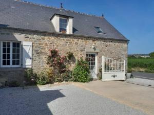 a stone house with a white gate and flowers at Gîte tante Jeanne in Réville